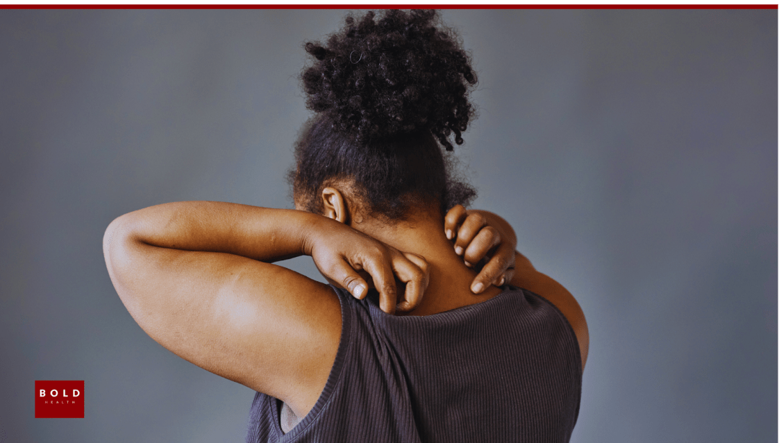 A person sitting on a sofa with their hand over their chest, illustrating the physical sensations of somatic anxiety and chest tightness.
