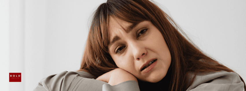 An anxious woman resting her head on her arm, illustrating OCD-related distress and misconceptions.