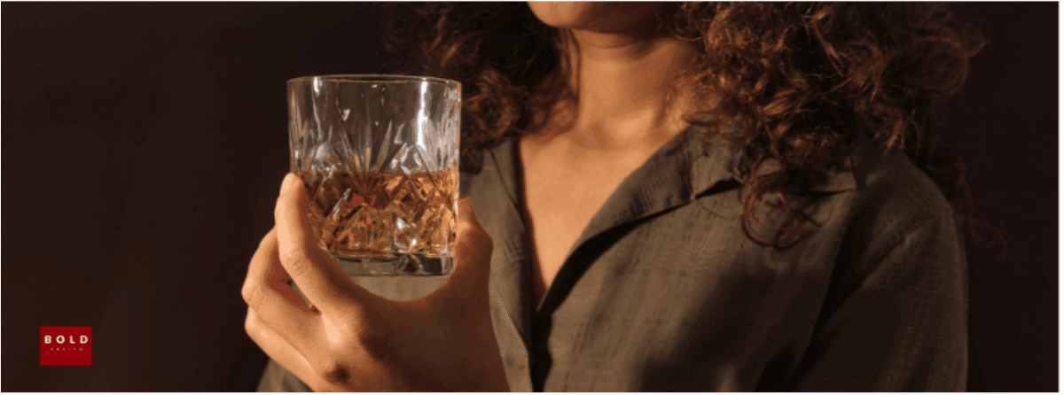 Close-up of a woman holding a glass of whiskey, emphasizing moderation and wellness benefits.