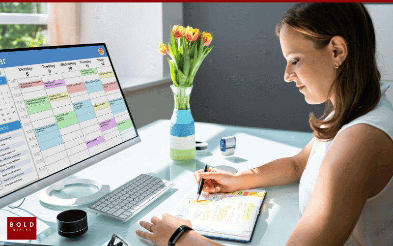 Woman reviewing her schedule and notes at desk, planning her step down from IOP, with calendar and flowers nearby.
